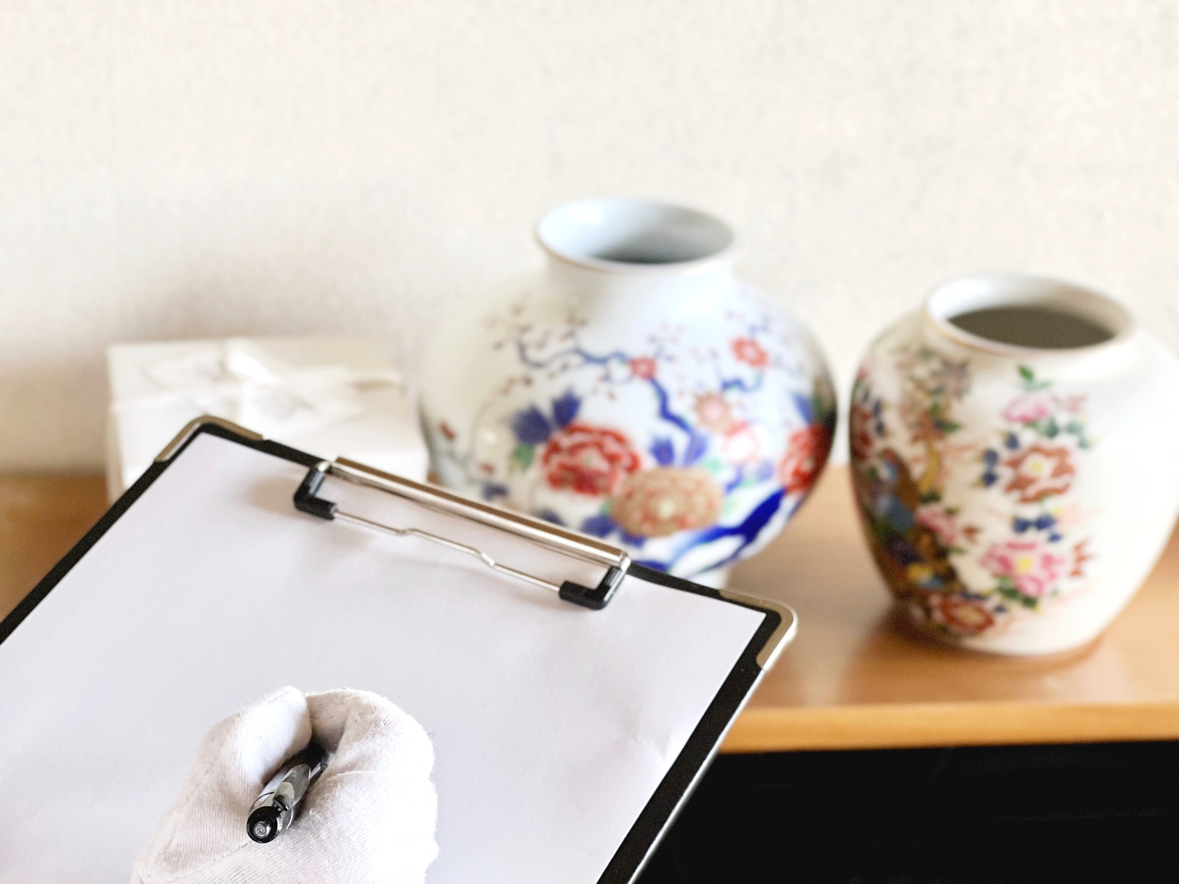 2つの壺と箱を査定するクリップボードと白手袋